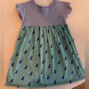 Mixed print dress with stripes on top and sharks, sun, wave print on the bottom.